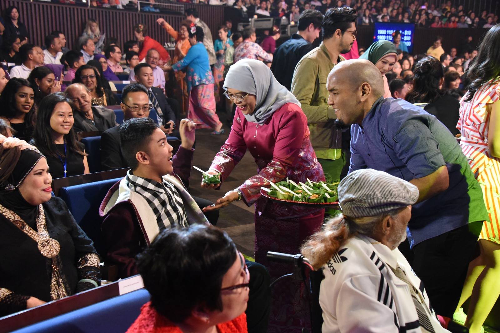 President Halimah Yacob distributing Pulut Inti (a traditional Peranakan dish)to the audience before the show. 