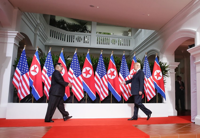 US President Donald Trump and North Korean leader Kim Jong Un walk past the flags of their countries at the DPRK-USA Singapore Summit. Photo courtesy: Ministry of Communications and Information