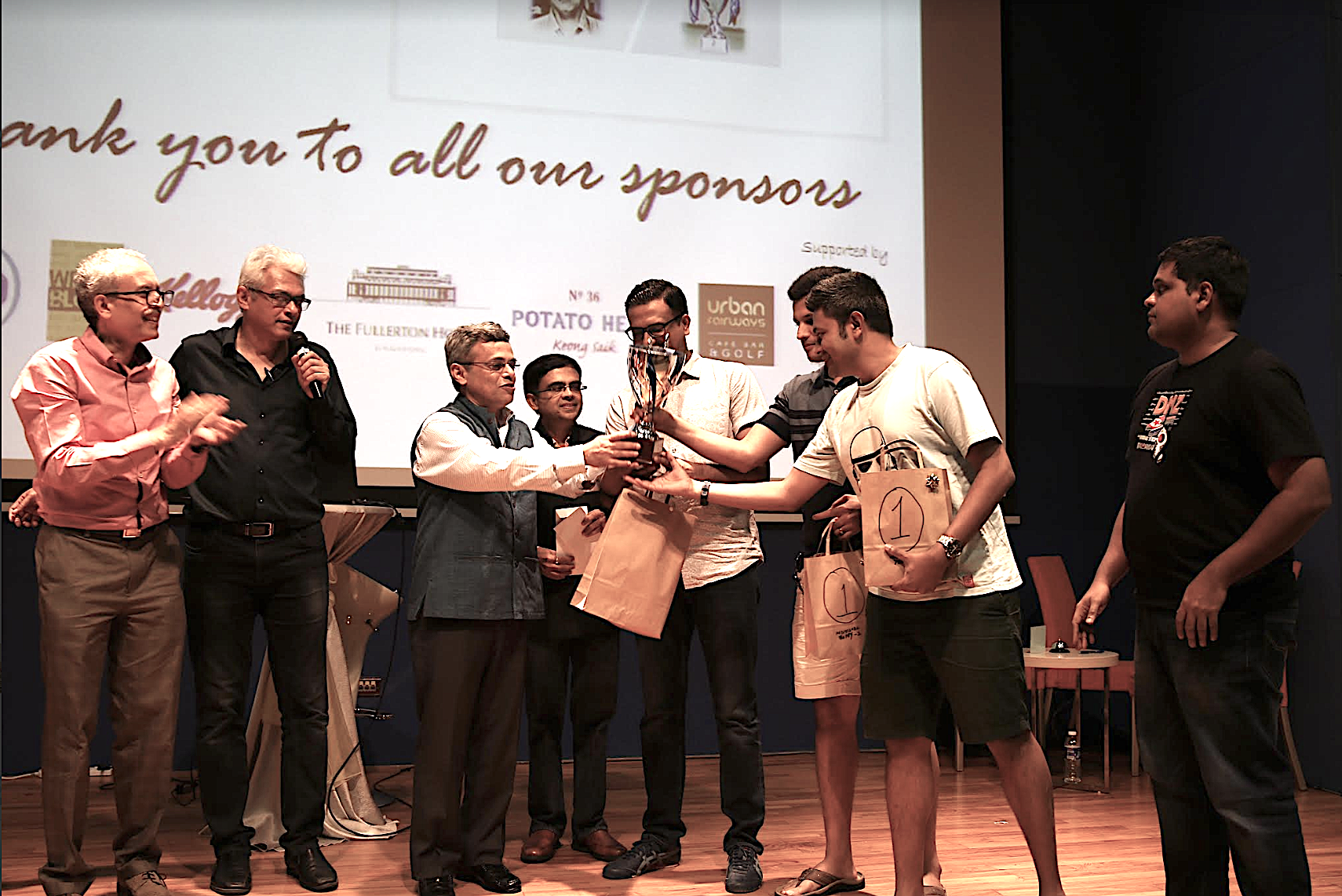 Indian High Commissioner, HE Jawed Ashraf presenting the trophy to the winning team of Mind aMaze 2017 Instant Noodles, as quizmaster Joy Bhattacharya and president of IIMPACT Saniv Aiyar (left) look on. Photo courtesy: Mind aMaze