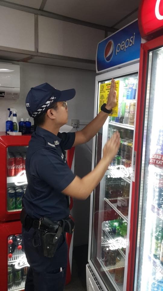 A Singapore Police Officer pasting advisory stickers at liquor outlets in Little India. Photo courtesy: Singapore Police 