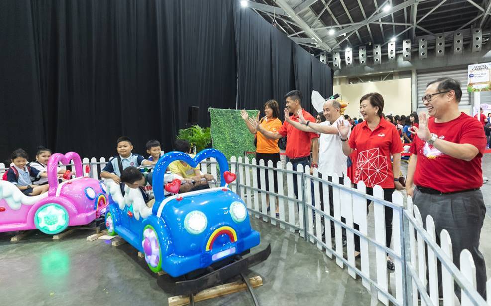Members of Singtel’s management Yuen Kuan Moon, Chairman of the STLF and CEO Consumer Singapore at Singtel (standing, third from left); Group CEO Chua Sock Koong (standing, second from right), and Arthur Lang, CEO, International (standing, first from right) waving to special needs students as they take a train ride. Photo courtesy: Singtel