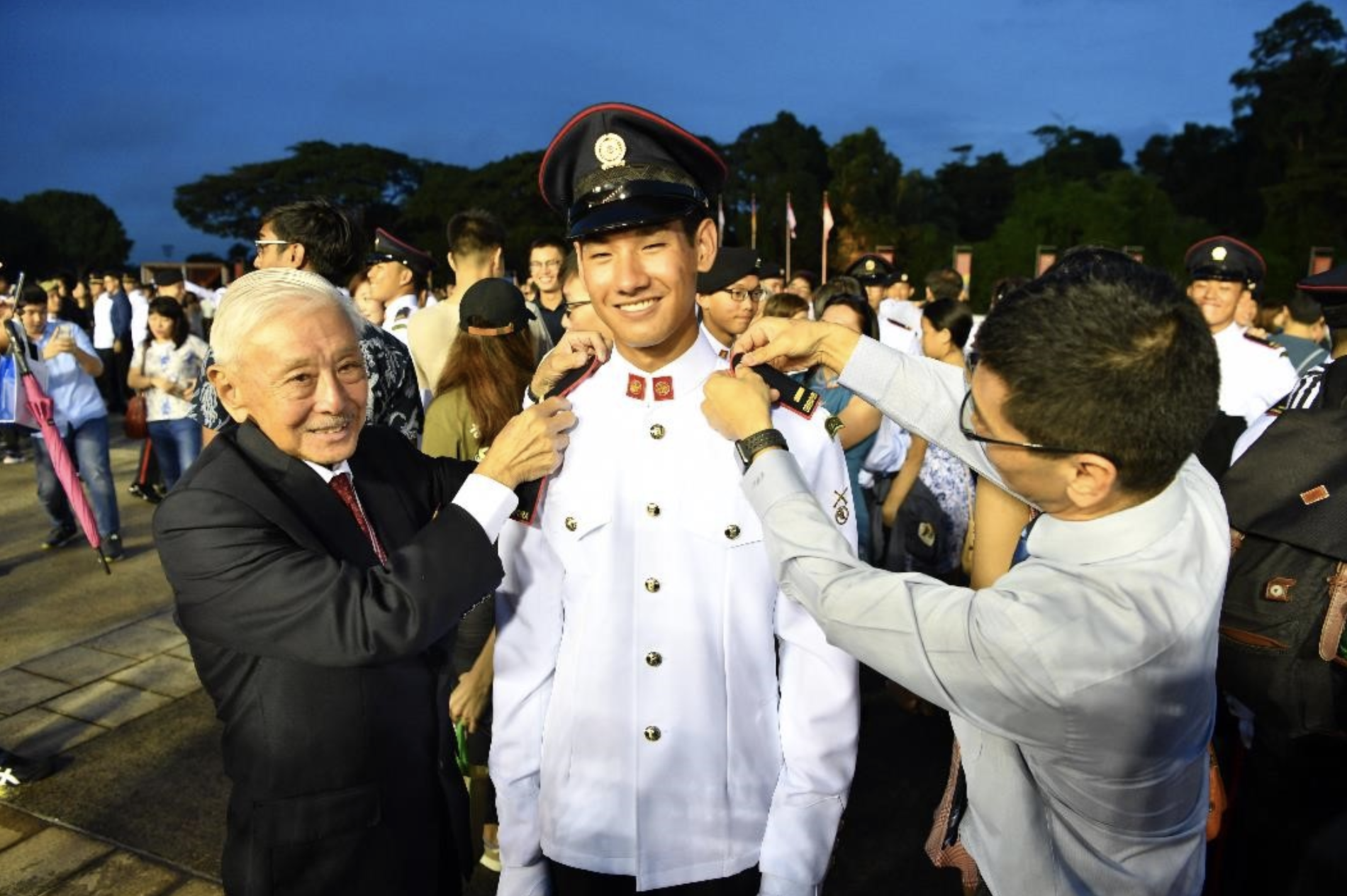 Newly-commissioned 2nd Lieutenant (2LT) Daniel Choo’s grandfather LG (RET) Winston Choo and his father Warren Choo affixing the 2LT rank on to his uniform at the parade. Photo courtesy: Mindef