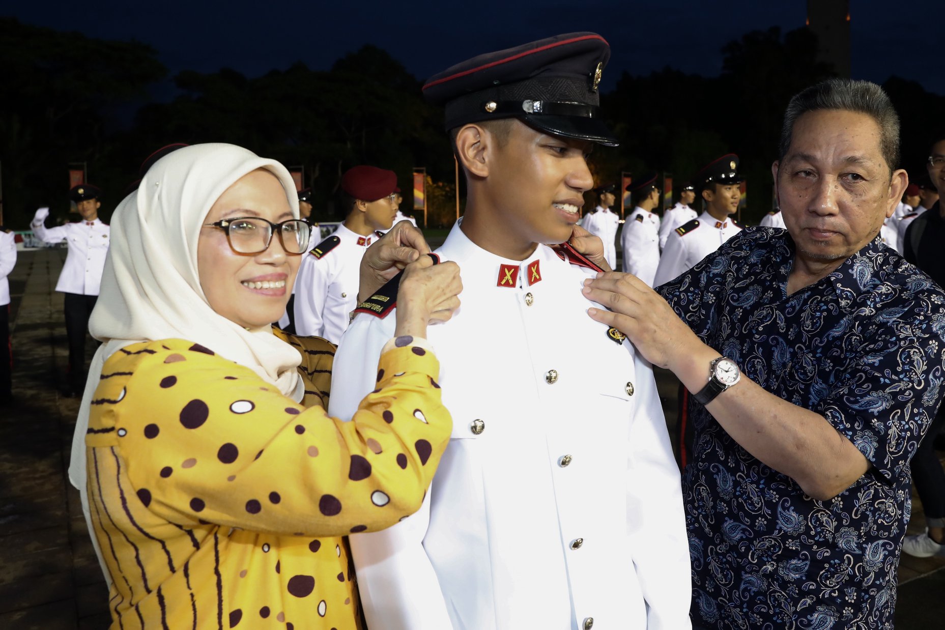 Proud parents of 2LT Muhamad Fudhail bin Abdul Latiff affixing his rank insignias on his shoulder. Photo courtesy: MCI Clement