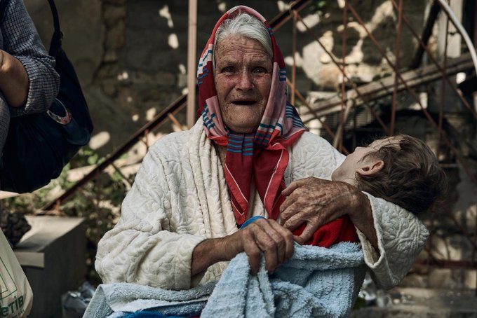 An elderly woman is holding her grandson. They were rescued from occupied territory.