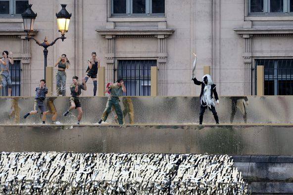 Hooded figure with the Paris Olympic flame